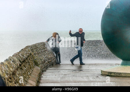 Un giovane cerca di scappare le onde durante una tempesta sul lungomare di Brighton Foto Stock