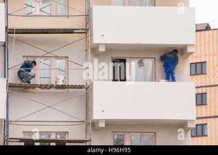 Anapa, Russia - 16 Novembre 2016: i lavoratori di eseguire la finitura e la pittura la facciata di edifici ad alta Foto Stock