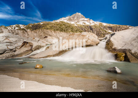 L'inizio del Rodano che scorre dal piccolo lago sotto Rhonegletscher Foto Stock