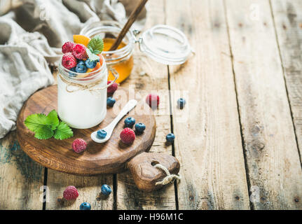 Il vasetto di vetro di yogurt con frutti di bosco, menta e miele Foto Stock