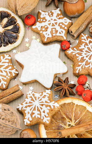 Natale in casa a forma di stella gingerbread cookies, noci, spezie bacche rosse marrone su carta da imballaggio sfondo Foto Stock