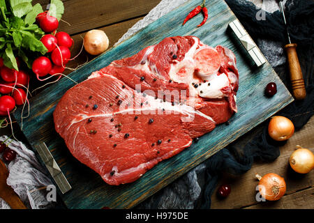 Carni fresche bovine Carne di vitello su tavola in legno rustico con verdure fresche, vista dall'alto Foto Stock