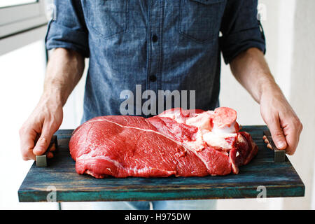 Uomo di mani tenendo il vassoio rustico con il pezzo di carne di manzo, il fuoco selettivo Foto Stock