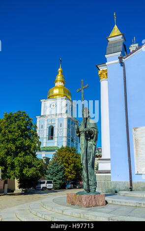 La statua di Sant'Andrea il primo chiamato con il campanile del monastero di San Michele con la cupola dorata sullo sfondo, Kiev, Ucraina Foto Stock