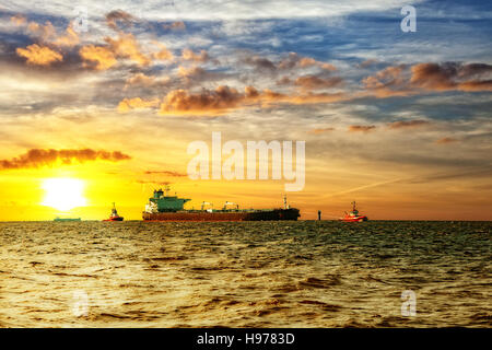 Nave cisterna con la scorta rimorchiatori sul mare a sunrise. Foto Stock