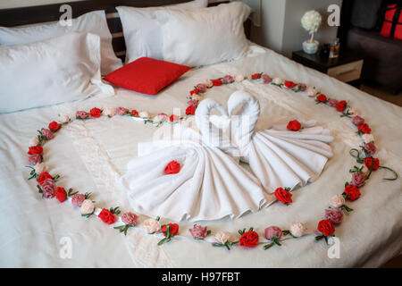 Due asciugamani bianchi cigni sul foglio di letto, decorato in rosa e cuore  in camera di albergo Foto stock - Alamy