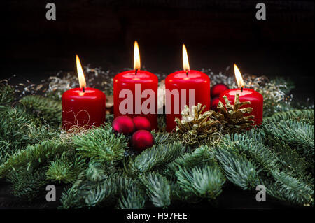 Avvento decorazione rosso quattro candele accese, baubles di natale e rami di alberi Foto Stock