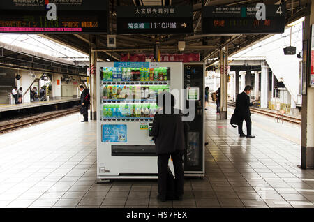 Vecchio giapponese donne inserimento di moneta nella macchina distributrice automatica acquistare bevande analcoliche tra attendere il treno alla Stazione di Ikebukuro in Shinjuku city il 19 ottobre Foto Stock