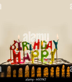 Buon compleanno candele accese su una torta isolati su sfondo bianco o grigio. Lettere colorate. vuota copia spazio per l'iscrizione. Foto Stock
