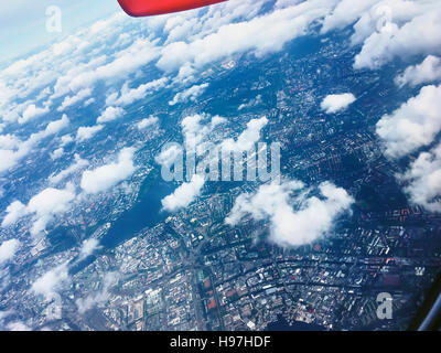 Volo sopra white cumulus nubi in un aereo con il wingtip e sentiero di vapori visibili in una soleggiata cielo blu in un concetto di trasporto Foto Stock