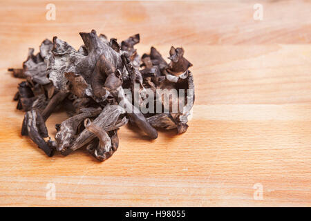 Corno dell'abbondanza di funghi luce sul tagliere di legno. Primo piano Foto Stock