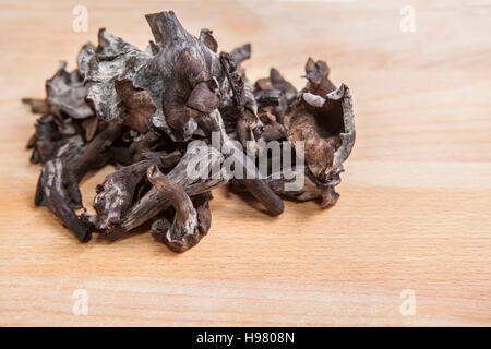 Corno dell'abbondanza di funghi luce sul tagliere di legno. Primo piano Foto Stock