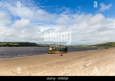 Una vecchia barca arrugginito sulla spiaggia del Fiume Tywi sotto un cielo blu con alcune nuvole, Ferryside, Glan-y-fferi, comunità di St Ismaele, Carmarthenshire, Foto Stock