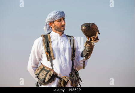 Dubai, UAE, Novembre 19th, 2016: Una falconer in abito tradizionale, la formazione di un Harrier Hawk (Polyboroides typus) Foto Stock