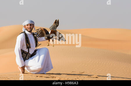 Dubai, UAE, Novembre 19th, 2016: Una falconer in abito tradizionale, la formazione di un Harrier Hawk (Polyboroides typus) Foto Stock