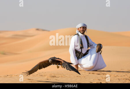 Dubai, UAE, Novembre 19th, 2016: Una falconer in abito tradizionale, la formazione di un Harrier Hawk (Polyboroides typus) Foto Stock