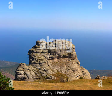 Colonne in pietra sotto forma di strati di lava sopra la valle e il villaggio. Crimea Foto Stock