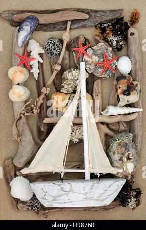 Decorativo in barca a vela su sfondo astratto con conchiglie, driftwood, di rocce e di alghe sulla sabbia. Foto Stock