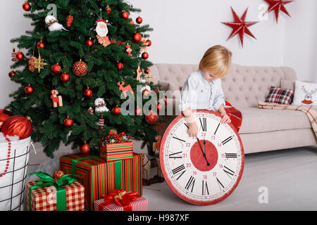 Ragazzo con un grande orologio nella struttura ad albero di Natale Foto Stock