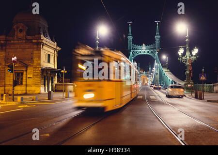 Vista notturna al ponte della Libertà a Budapest con i tram che passa Foto Stock