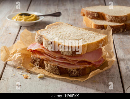 Una carne affumicata panino su di un tavolo di legno con mostarda. Foto Stock