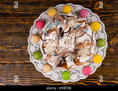 Vista superiore della casalinga torta di compleanno con un sacco di candele accese nei pressi di diverso colore, macarons sulla scrivania in legno Foto Stock