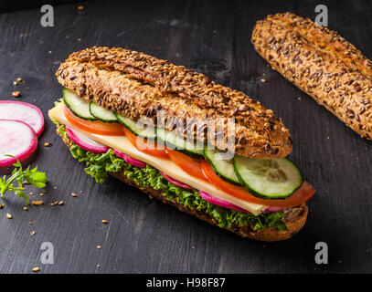 Sandwich con formaggio, pomodoro, cetriolo, ravanello e lattuga. Dark e moody. Foto Stock
