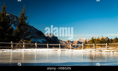 Iced piccolo lago delle Alpi italiane in una soleggiata giornata invernale Foto Stock