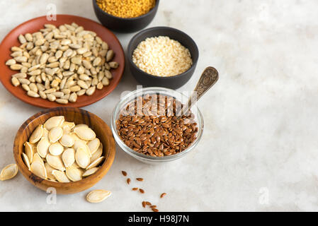 Olio assortiti (semi di lino, sesamo, zucca, girasole, senape) su sfondo di pietra con copia spazio - ingredienti biologici per un sano vegetariano vegano Foto Stock