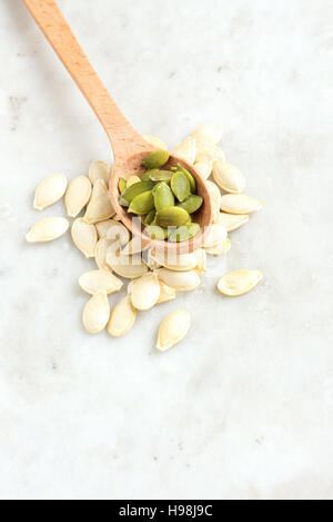 Semi di zucca su pietra bianca bsckground con spazio copia - il cibo sano ingrediente Foto Stock