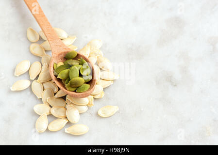 Semi di zucca su pietra bianca bsckground con spazio copia - il cibo sano ingrediente Foto Stock