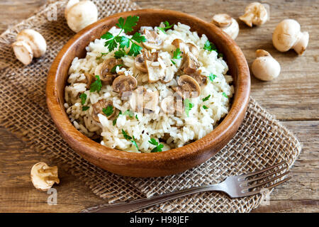 Risotto ai funghi con il prezzemolo nel recipiente di legno vicino - una sana alimentazione vegetariana Foto Stock
