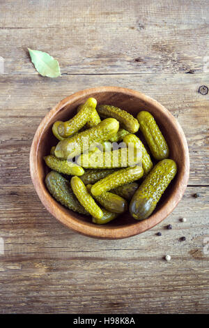 Pickles. Ciotola di cetriolini sottaceto (cetrioli) su legno rustico sfondo con copia spazio. Foto Stock