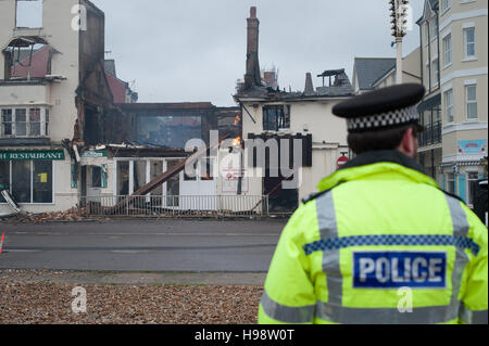 Un funzionario di polizia si erge davanti ad un fuoco-proprietà danneggiate a Bognor Regis, West Sussex, Regno Unito. Foto Stock