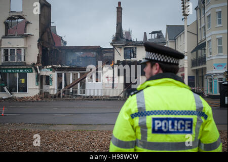 Un funzionario di polizia si erge davanti ad un fuoco-proprietà danneggiate a Bognor Regis, West Sussex, Regno Unito. Foto Stock