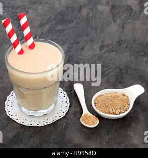Radice di Maca heath bere in un bicchiere con la polvere in un bianco cina ciotola e cucchiaio. Foto Stock