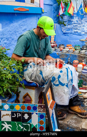 Un artigiano locale lavorando su tazze Souvenir al di fuori del suo negozio nella Medina, Chefchaouen, Marocco Foto Stock