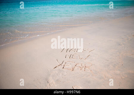 Felice Anno Nuovo scritto nella sabbia bianca Foto Stock