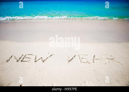 Felice Anno Nuovo scritto nella sabbia bianca Foto Stock