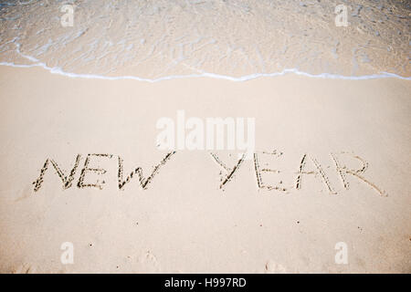 Felice Anno Nuovo scritto nella sabbia bianca Foto Stock