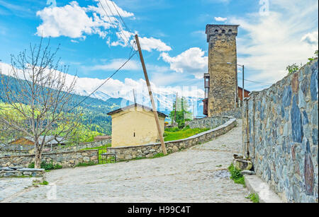 La vecchia strada di pietra con una piccola cappella del cimitero vecchio e torre Svan su sfondo, Mestia, Svaneti superiore, Georgia. Foto Stock