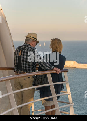 Due persone in piedi sul ponte di una nave da crociera, che guarda al mare. Foto Stock