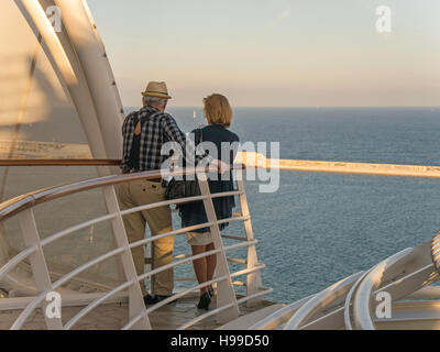 Due persone in piedi sul ponte di una nave da crociera, che guarda al mare. Foto Stock