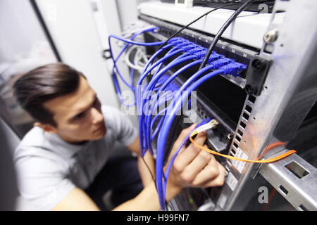 Uomo di collegamento dei cavi di rete a switch Foto Stock