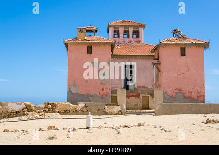 Grande rosa rovinato mansion dal portoghese di epoca coloniale nel piccolo villaggio costiero di Angola il deserto del Namib. Foto Stock