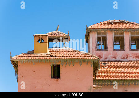 Grande rosa rovinato mansion dal portoghese di epoca coloniale nel piccolo villaggio costiero di Angola il deserto del Namib. Foto Stock