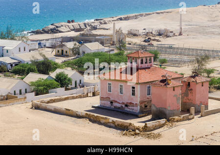 Grande rosa rovinato mansion dal portoghese di epoca coloniale nel piccolo villaggio costiero di Angola il deserto del Namib. Foto Stock