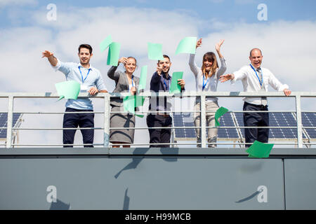 La gente di affari nella terrazza sul tetto gettando papers Foto Stock