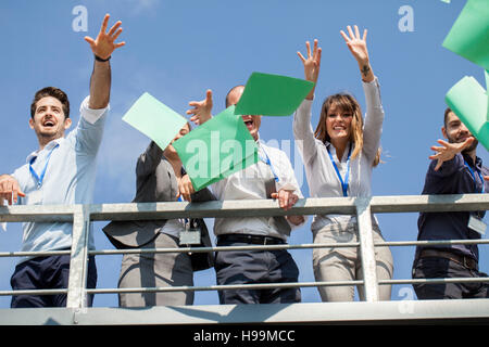 La gente di affari nella terrazza sul tetto gettando papers Foto Stock