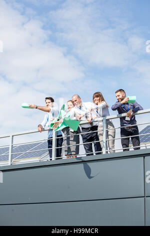 La gente di affari nella terrazza sul tetto gettando papers Foto Stock